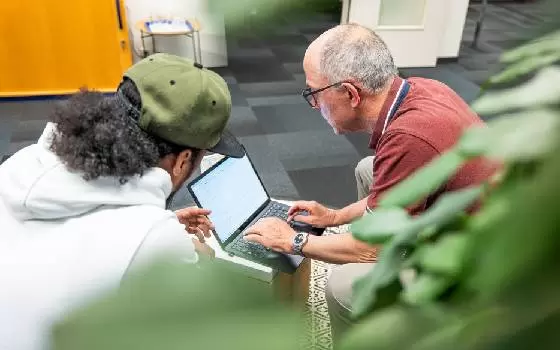 Zwei Männer sitzen gemeinsam an einem Laptop.